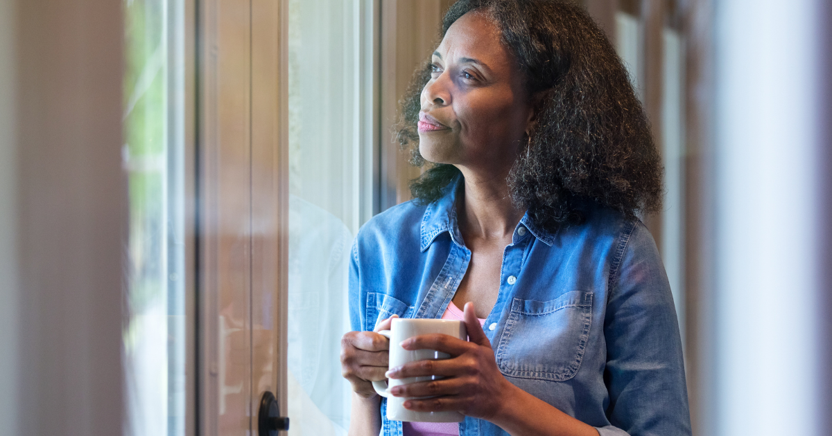 The images shows a person standing next to a window thinking about something highlighting the importance of self assessment 