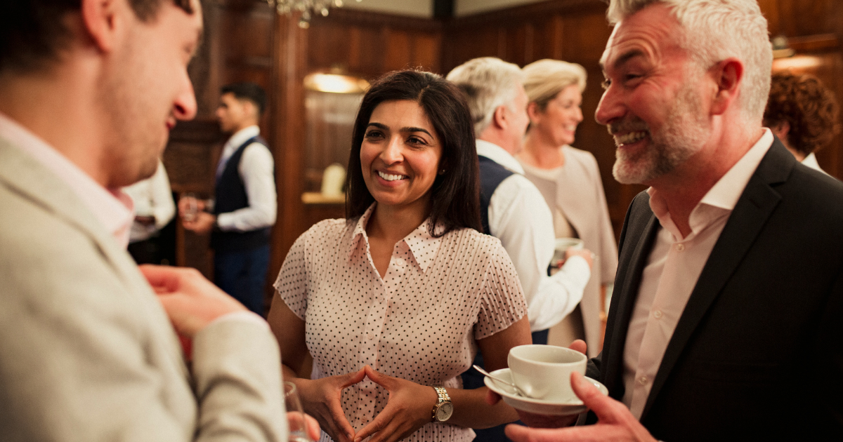 Three professionals chatting with each other in a gathering, highlighting this importance of mentorship and professional relationships