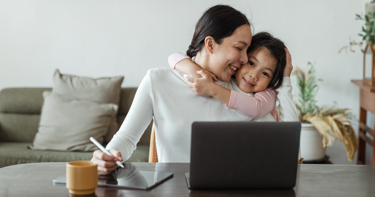 A woman with her daughter working on her laptop depicting the importance of work life balance